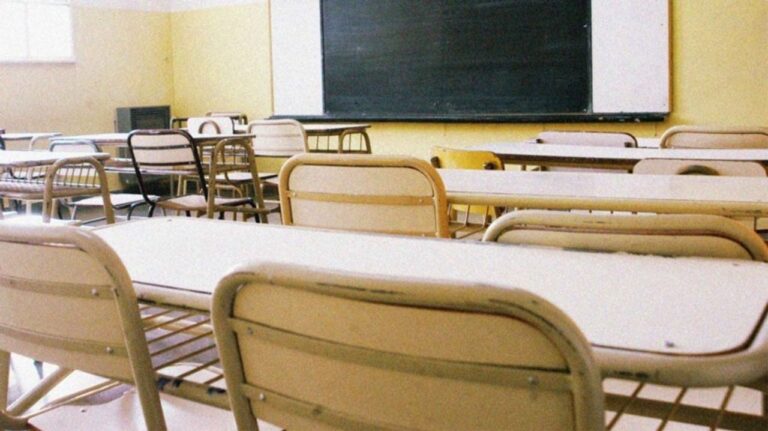 Fachada de una escuela con presencia policial simbólica