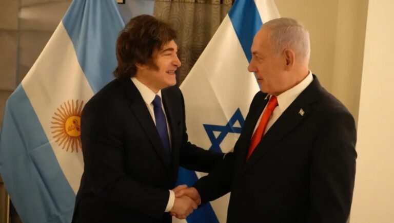 Presidente Javier Milei durante un acto diplomático, con banderas de Argentina e Israel de fondo.