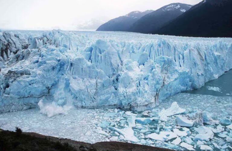 Vista aérea de un glaciar en la Patagonia Argentina, con montañas de fondo.
