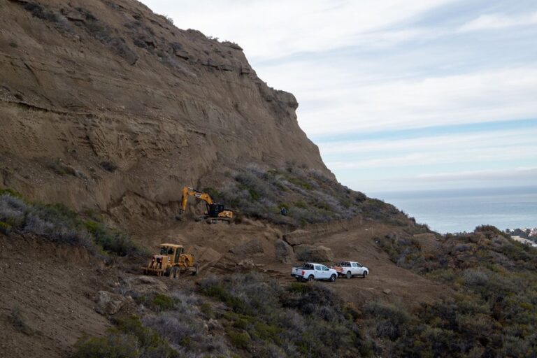 Maquinaria pesada trabajando en la ladera del cerro Hermitte en Comodoro Rivadavia